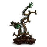 A Chinese bronze and enamel dragon figurine, set with turquoise coloured cabochons, on carved wooden