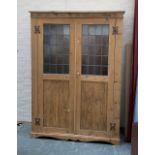 A large pine cupboard, the doors with lead glazed upper section, opening to an interior with hanging