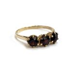 A 9ct gold garnet three stone ring, size R, 2.4g, in an Art Deco bakelite ring box