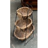 A wrought metal and wicker basket three tiered stand, 80cmH