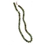 A Chinese jade bead necklace, the beads approx. 0.7cmD, in need of restringing, with a white metal