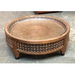 An Eastern worked copper tray set into a circular turned lattice base, 76cmD 27cmH