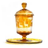 A 19th century Bohemian amber glass footed punch bowl, cover and stand, engraved with deer in a