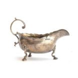A William IV silver sauce boat, London 1831, leaf capped handle and wavy edge, raised on three