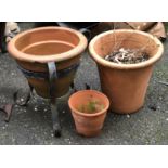 A terracotta pot on a wrought metal stand, 38cmH; together with two terracotta pots