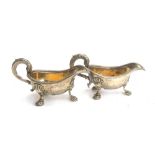 A pair of white metal sauce boats, each with leaf capped handle, raised on three feet, approx. 16cmL