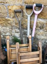 A pair of small wooden children's garden chairs together with a garden fork and 2 spades