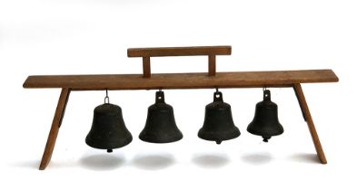 A set of four bells, pleasantly harmonious, suspended on a wooden stand, 60cmW