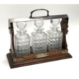 An oak and silver plated three decanter tantalus (no key, unlocked) with three matching cut glass