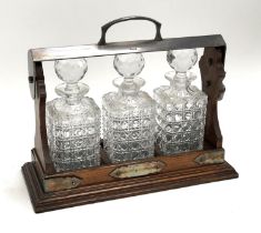 An oak and silver plated three decanter tantalus (no key, unlocked) with three matching cut glass