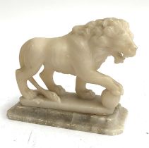 A carved alabaster figure of a lion with paw on an orb, 12cmH