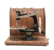 A Lead miniature sewing machine in hooped carry case