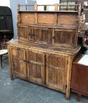 An elm dresser sideboard, the top with to shelves, over cupboards, on a base with three panelled