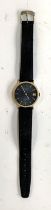 A vintage mens Rotary watch with black face and gold plate surround with leather strap