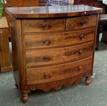 A Victorian bowfront mahogany chest, of two short over three long drawers, shaped apron and turned