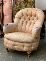 A Victorian button back armchair in need of reupholstery, on gilt turned legs and brass casters