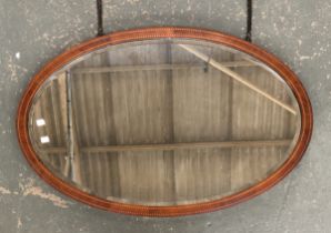 An Edwardian oval wall mirror, mahogany frame with barber's pole stringing, bevelled glass, 99x62cm