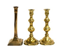 An 18th century brass reeded candlestick, on square base, 26cm high; together with a later pair