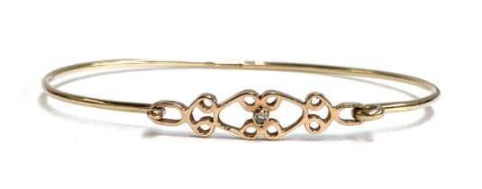 A 9ct gold bangle with Celtic style design, set with a small central diamond, 4.2g