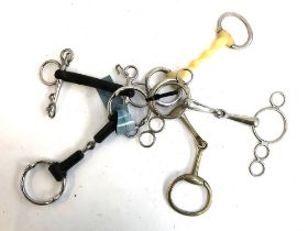 A collection of bits, 5-5.5", including vulcanite Pelham, rubber straight bar snaffle, three ring