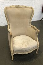 A continental cream painted barrel back armchair with carved frame, feather filled squab cushion,