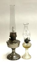 Two oil lamps: one glass, one plate metal, each with glass chimney, 60cmH and 40cmH