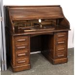 An oak rolltop desk, with tambour opening to a fitted interior, over a kneehole and eight drawers,