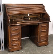 An oak rolltop desk, with tambour opening to a fitted interior, over a kneehole and eight drawers,