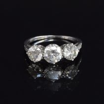 An 18ct white gold diamond trilogy ring, the shoulders studded with diamonds, the three brilliant