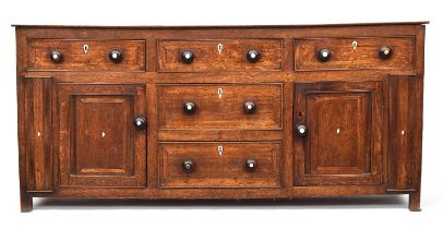 A George III oak dresser base, comprising three drawers, two central drawers flanked by cupboard