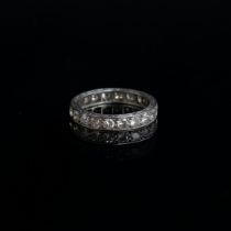 An Art Deco platinum and diamond full eternity ring, hand engraved scrolling decoration to edges,