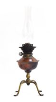 Attributed to W.A.S. Benson, a brass and copper oil lamp, on four feet, with glass chimney,