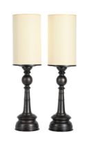 A pair of patinated metal table lamps, each with a card shade to simulate an oversized candle above