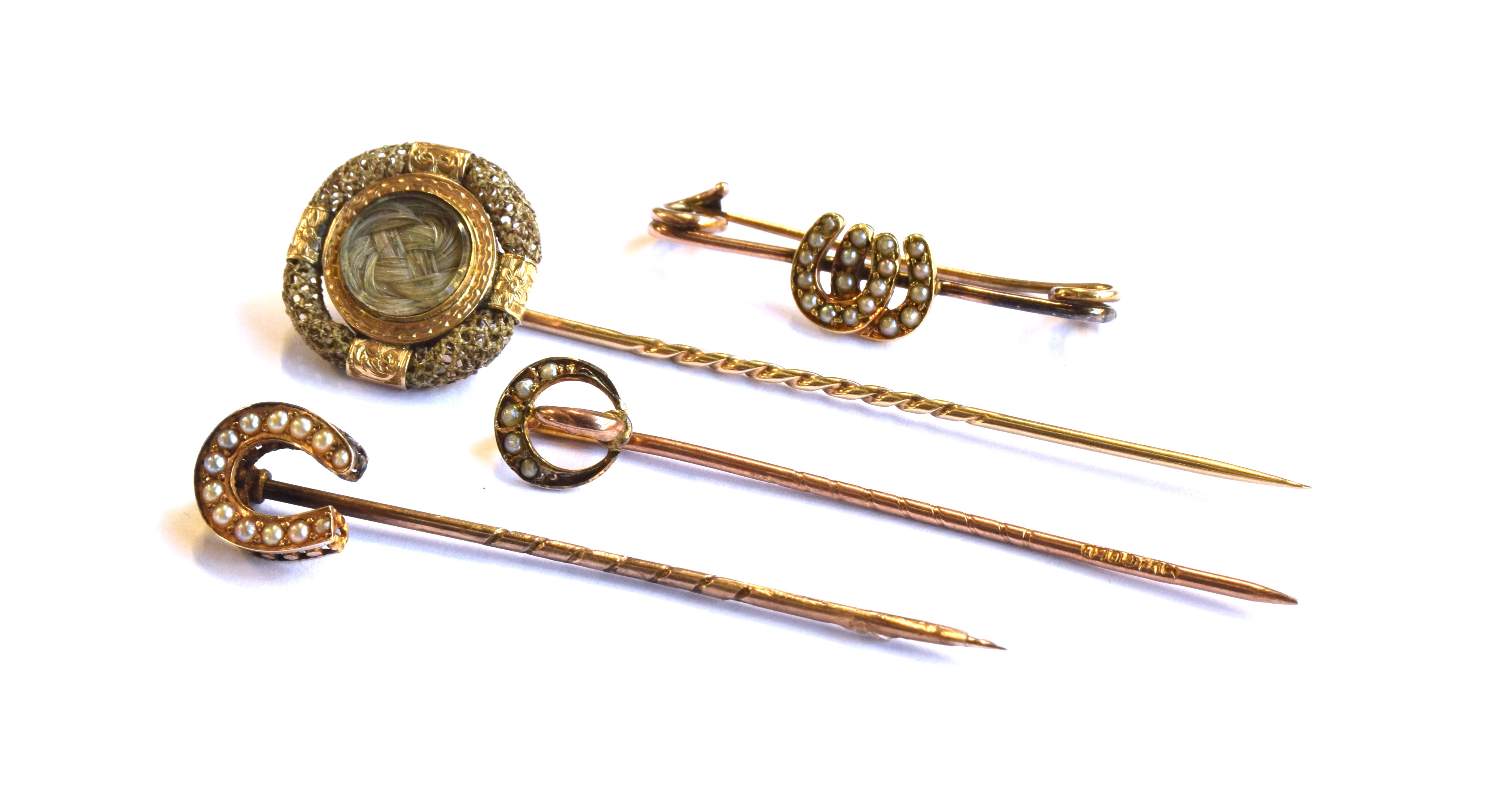 A gold mounted Victorian hair work stick pin, the glazed compartment having plaited hair, surrounded