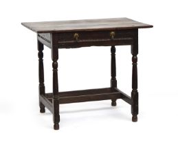 A 17th century oak side table, plank top with cleated ends, single carved frieze drawer, on reel