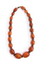An amber bead necklace with white metal granulated bead spacers, the amber beads graduating from 1.