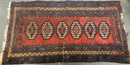 A Persian rug with six central hooked lozenges within a triple border, 196x103cm