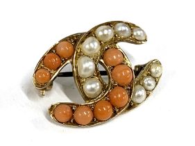 A Victorian gold brooch in the form of interlocking horseshoes set with pearls and coral