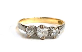 An 18ct gold trilogy ring, set with two diamonds and a central paste replacement stone, size L, 2g