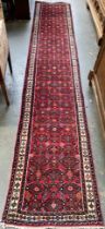 A red ground runner rug, 400x71cm