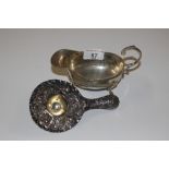 A silver strainer with floral decoration and a sil