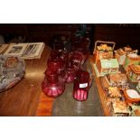 A collection of seven cranberry glass jugs