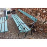 A wooden and metal garden bench with scroll arms