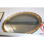 A gilt framed and bevel edged oval wall mirror