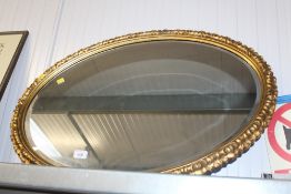 A gilt framed and bevel edged oval wall mirror