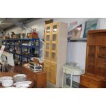 A beech glazed display cabinet raised on cupboard