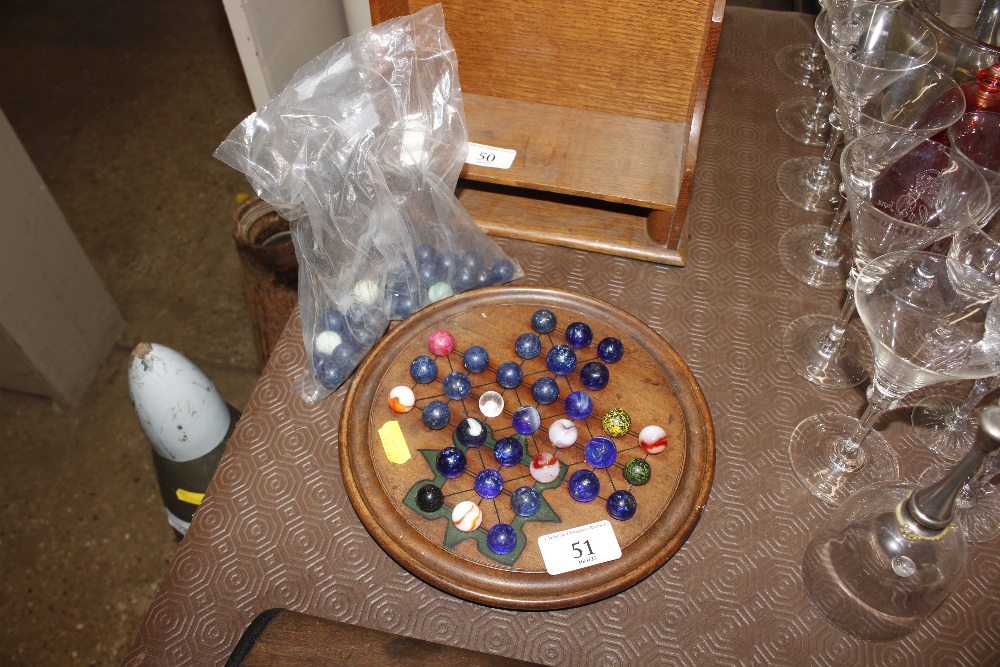 An inlaid solitaire board and various marbles