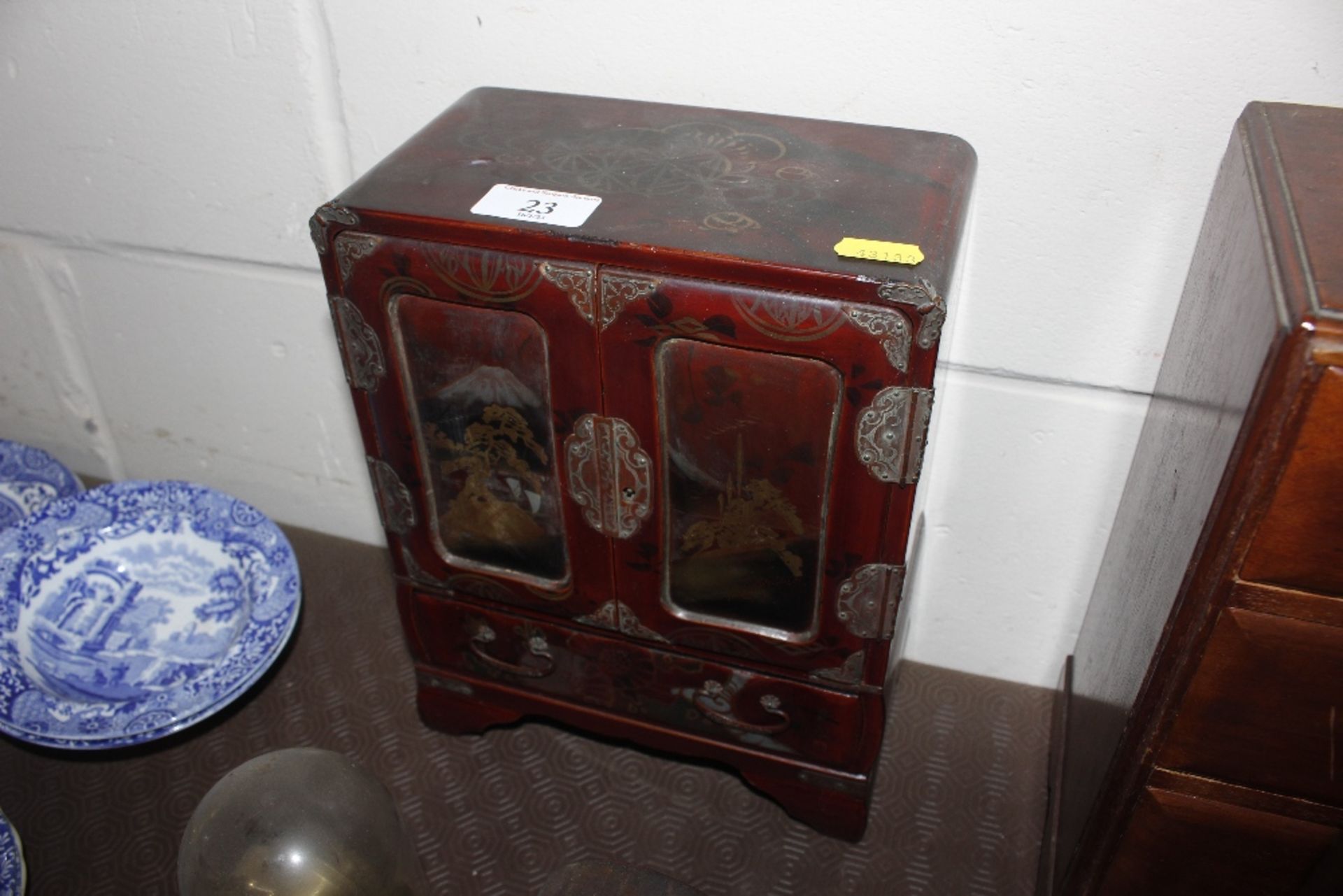 An Oriental lacquered trinket cabinet enclosed by