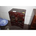 An Oriental lacquered trinket cabinet enclosed by