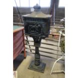A cast metal post box on stand with decorative pan